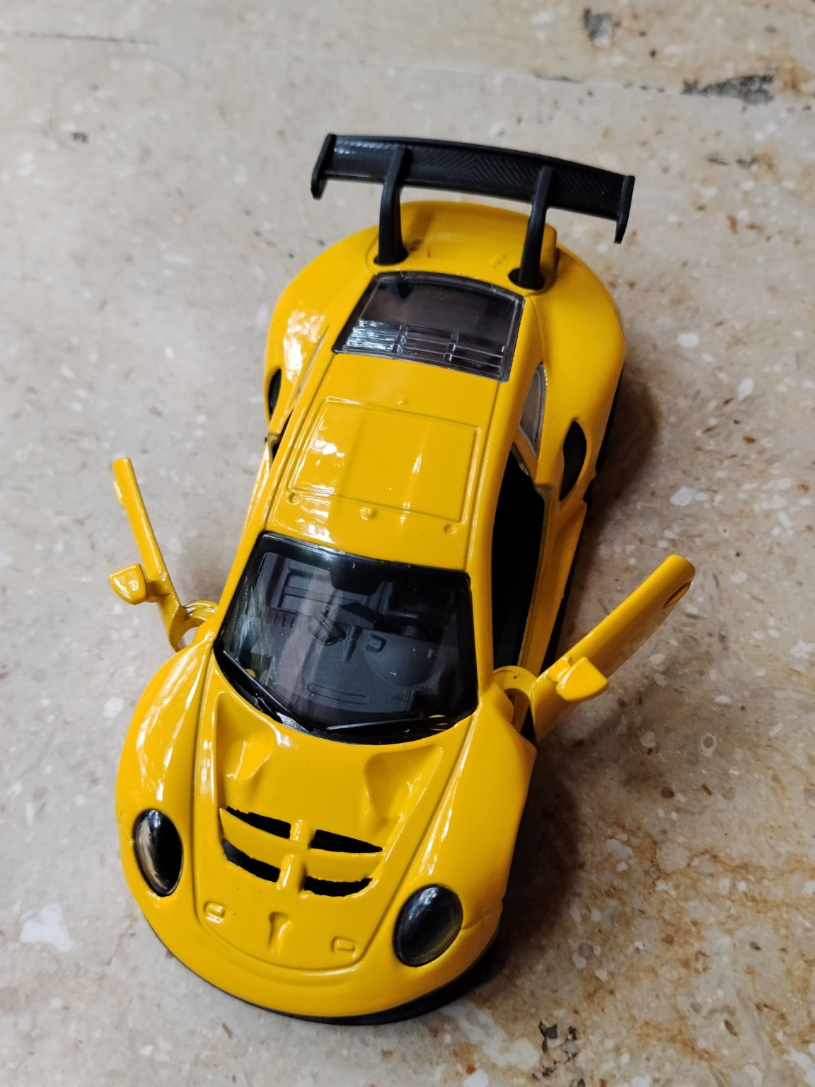 Yellow die-cast metal supercar toy with opening doors