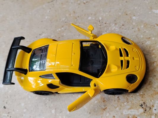 Yellow die-cast metal supercar toy side view with opening door
